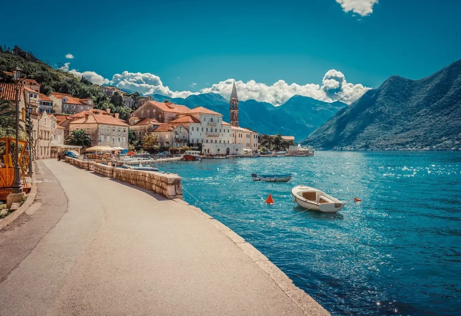 The Perast waterfront with the bell tower of St Nicholas and boats in the bay