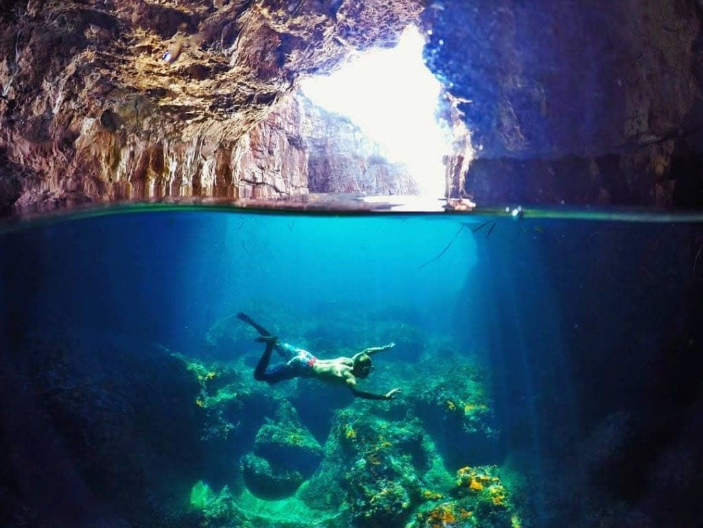 Inside the Blue Cave, a swimmer above the lit seabed